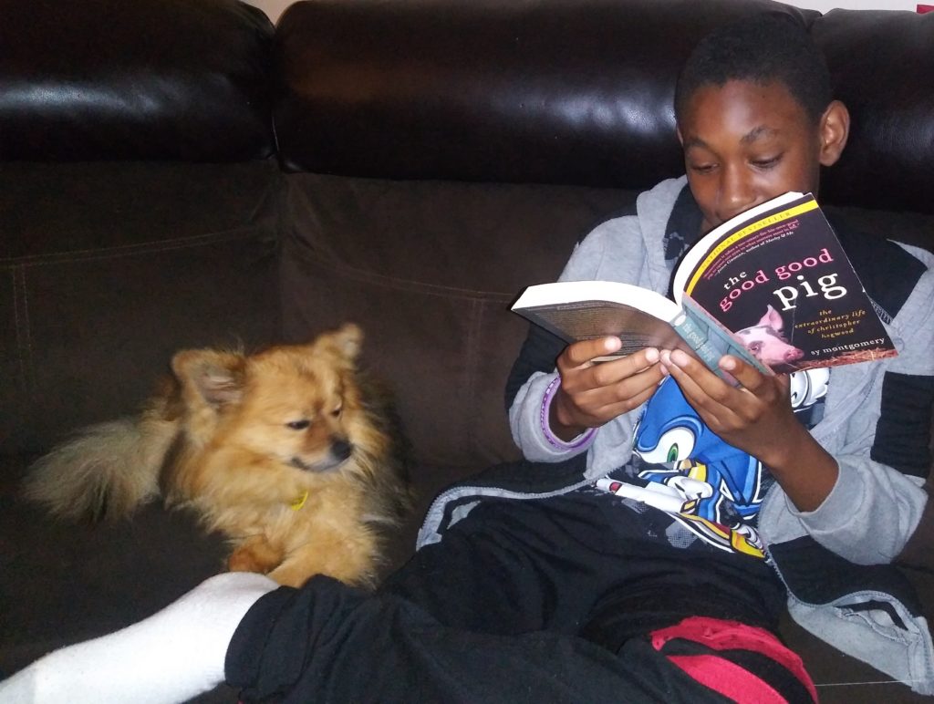 Jayden, age 12, sits down to read The Good Good Pig with his dog Monty